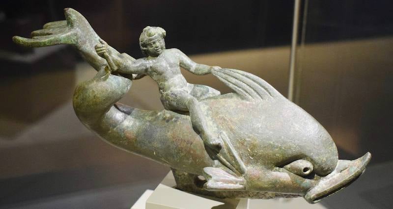 Bronze statuette of Eros riding a dolphin displayed in a case at the Ephesus Archaeological Museum
