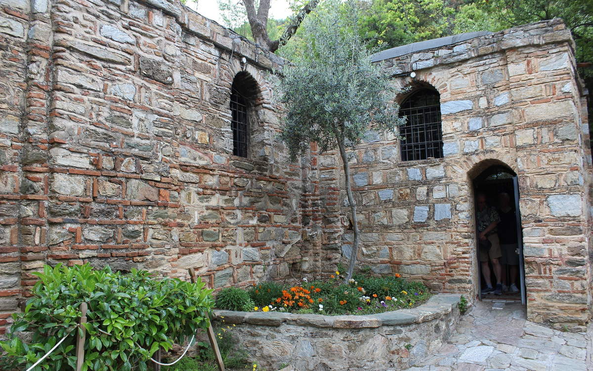 The arched stone doorway into the House of the Virgin Mary, with an old olive tree growing against the wall beside it