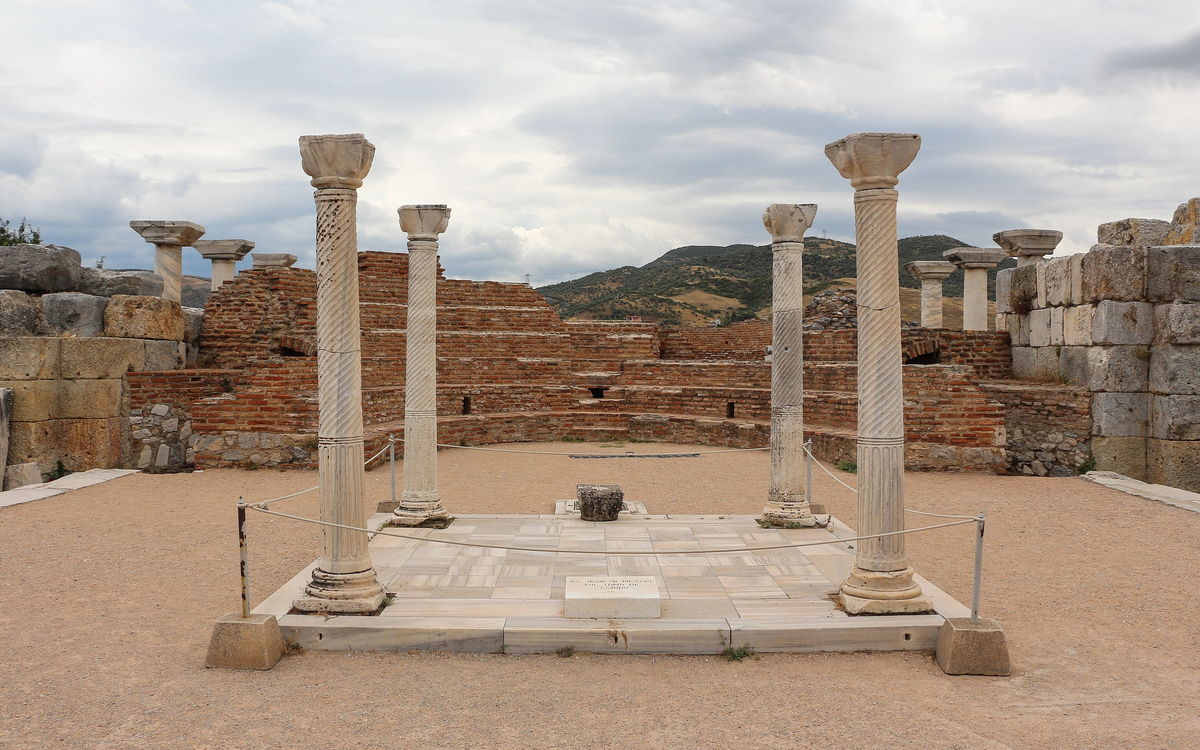Four marble columns standing around the raised marble slab that marks the tomb of St John in the basilica at Selçuk